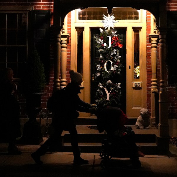 A woman pushes a stroller in front of a house decorated with a Moravian star and Christmas wreaths in Bethlehem, Pa., on Sunday, Dec. 1, 2024. (AP Photo/Luis Andres Henao)