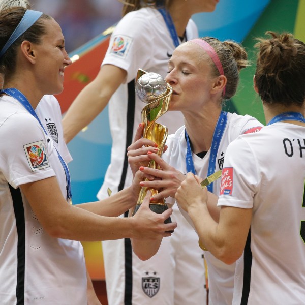 FILE _ United States' Becky Sauerbrunn, right, kisses the trophy as Lauren Holiday, left, and Kelley O'Hara, right, look on after the U.S. beat Japan 5-2 in the FIFA Women's World Cup soccer championship in Vancouver, British Columbia, Sunday, July 5, 2015. (AP Photo/Elaine Thompson, File)