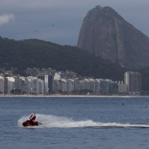 A firefighter dressed as Santa Claus drives a Jet Ski by Copacabana Beach in Rio de Janeiro, Tuesday, Dec. 17, 2024. (AP Photo/Bruna Prado)