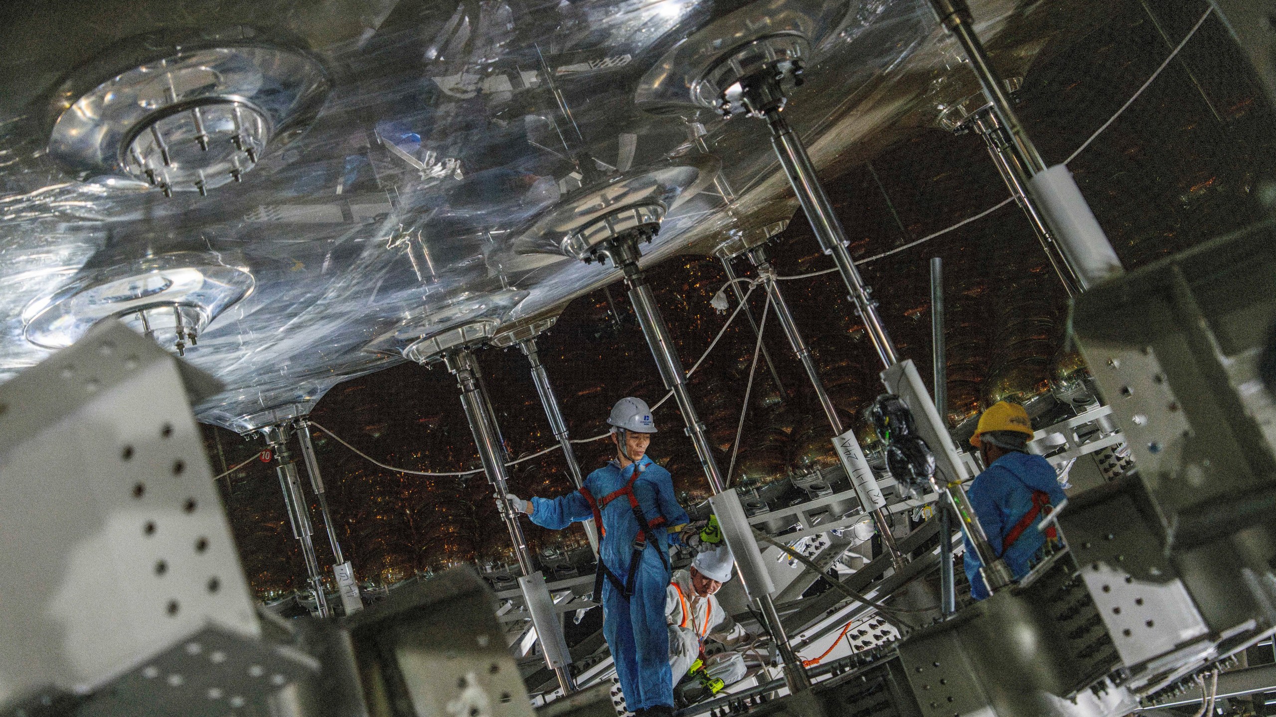 Workers labor on the underside of the cosmic detector located 2297 feet (700 meters) underground at the Jiangmen Underground Neutrino Observatory in Kaiping, southern China's Guangdong province on Friday, Oct. 11, 2024. (AP Photo/Ng Han Guan)