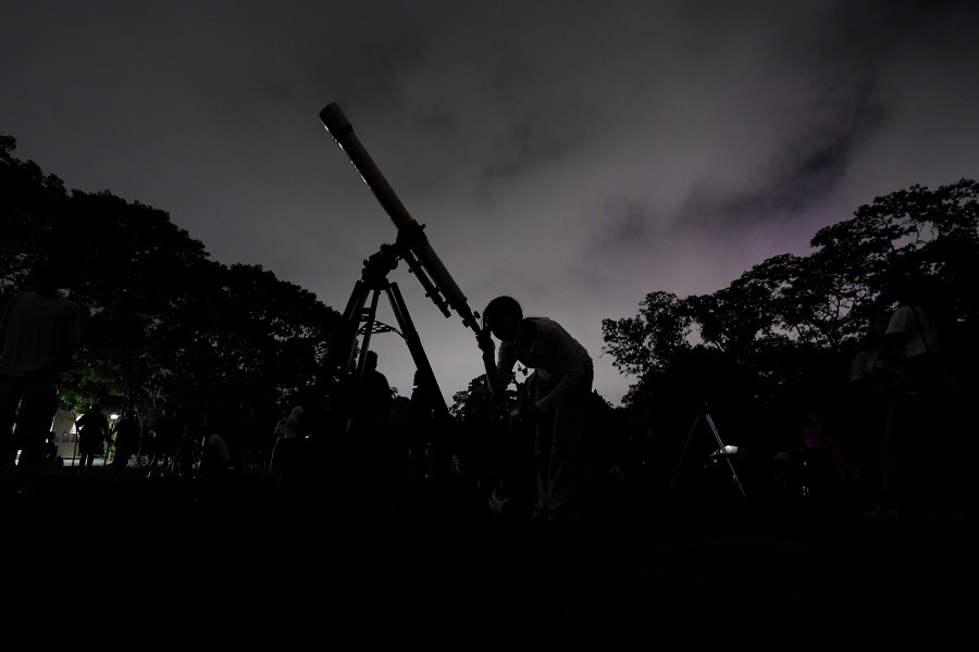 FILE - A girl looks through a telescope in Caracas, Venezuela, on Sunday, May 15, 2022. (AP Photo/Matias Delacroix, File)