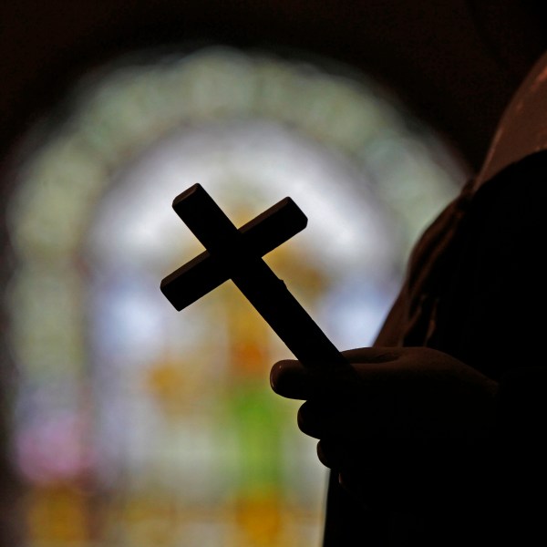 FILE - This Dec. 1, 2012 file photo shows a silhouette of a crucifix and a stained glass window inside a Catholic Church in New Orleans. (AP Photo/Gerald Herbert, File)