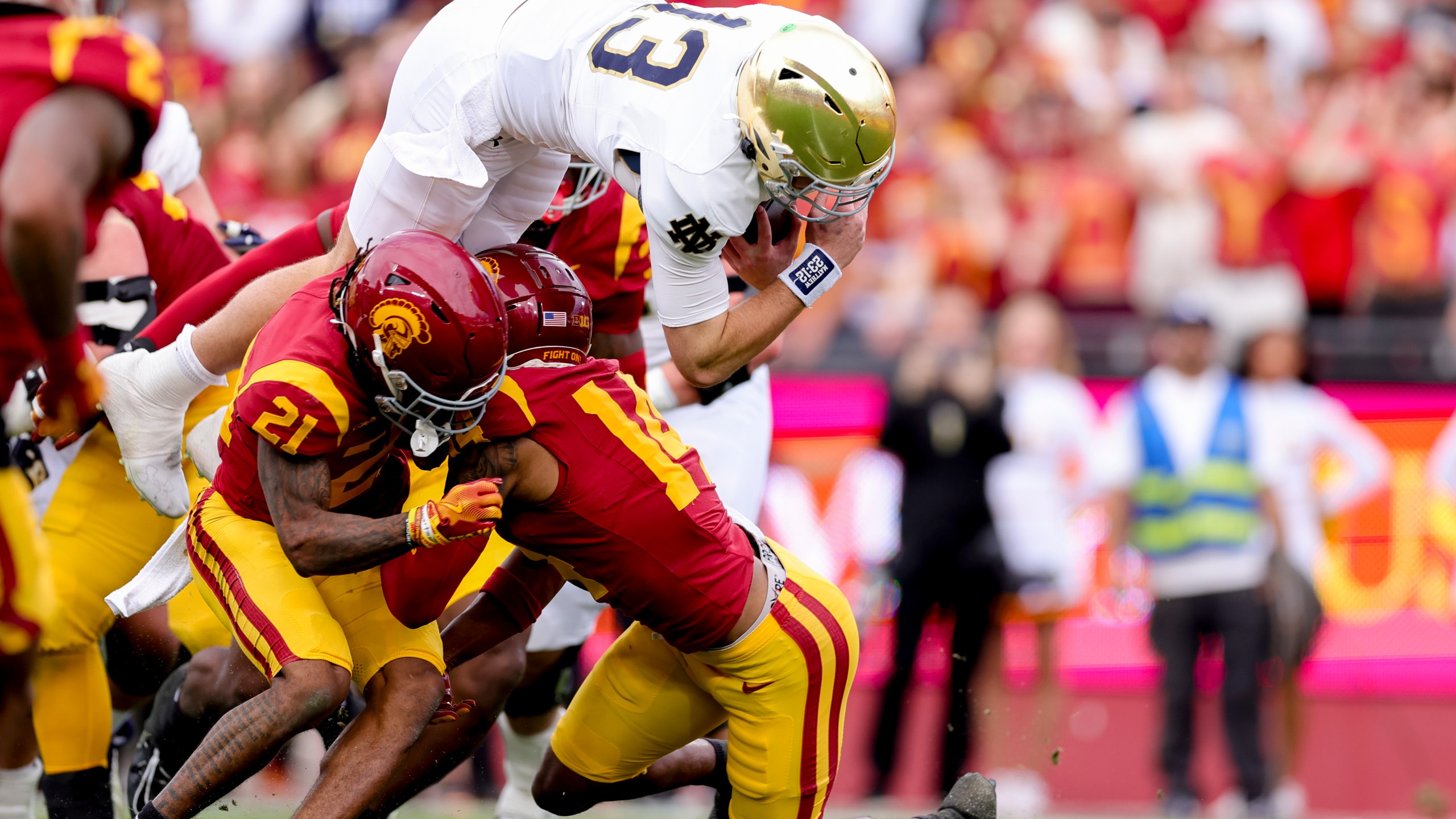 Notre Dame quarterback Riley Leonard, top, dives over Southern California cornerback Greedy Vance Jr., left, and cornerback Jacobe Covington during the first half of an NCAA college football game against Southern California, Saturday, Nov. 30, 2024, in Los Angeles. (AP Photo/Ryan Sun)