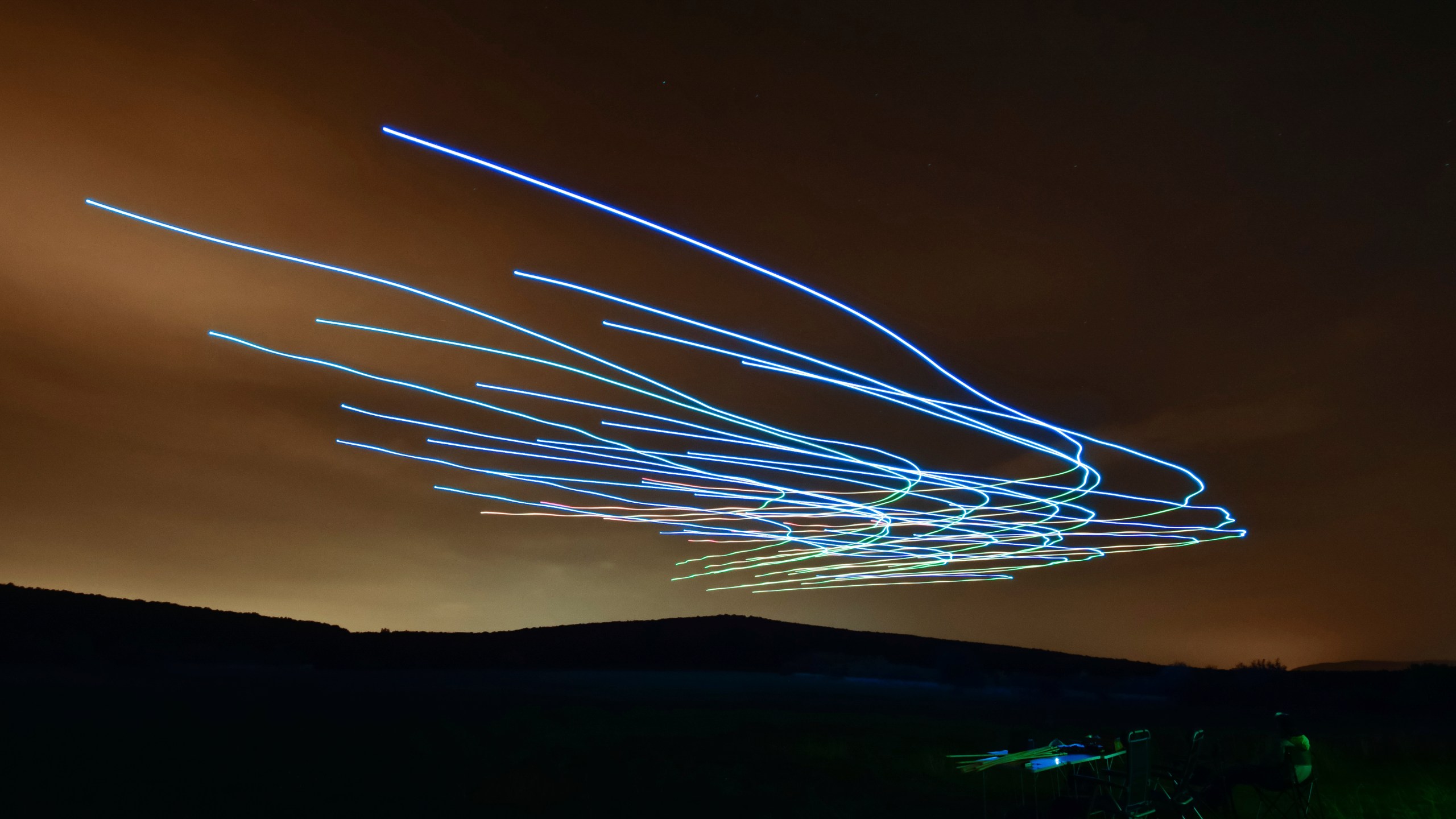 This handout photo taken with long exposure shows a researcher of the Eötvös Loránd University observing the flight of a flock of autonomous drones during an experiment near Budapest, Hungary, Thursday, Oct. 21, 2021. (AP Photo/HO/Eotvos Lorand University)