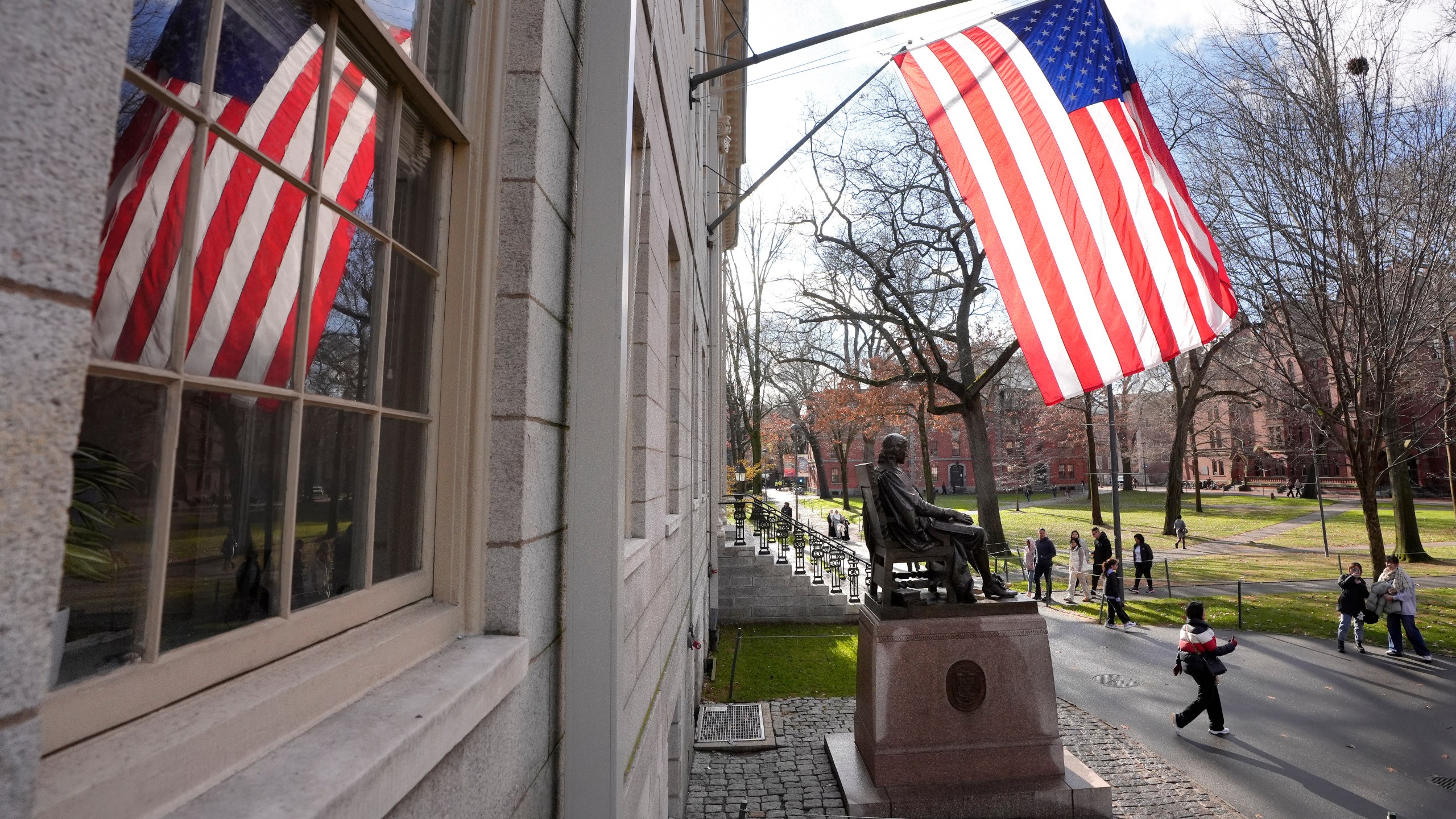 People walk past the John Harvard statue in Harvard Yard, Tuesday, Dec. 17, 2024, on the campus of Harvard University in Cambridge, Mass. (AP Photo/Steven Senne)