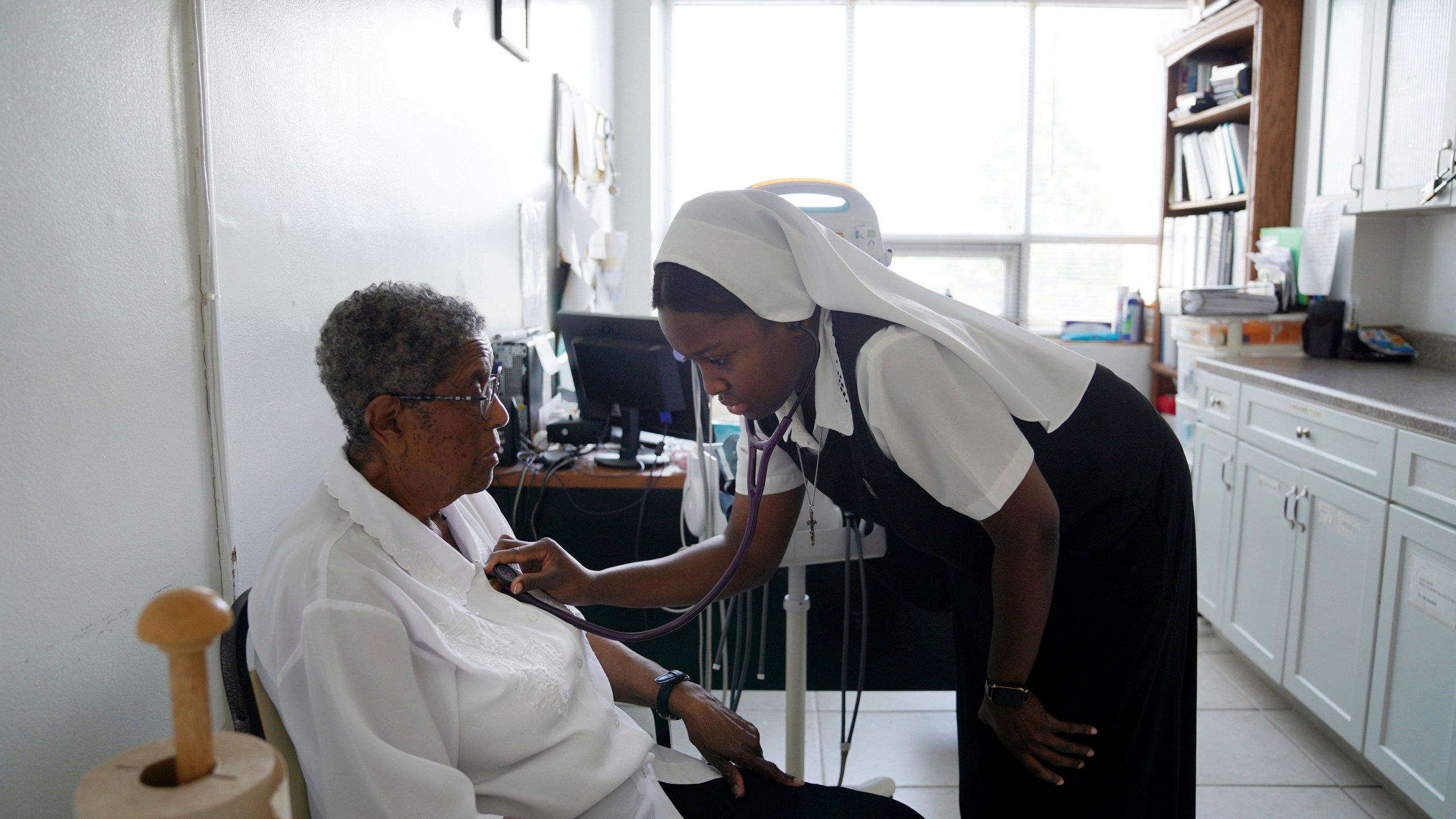 Sister Seyram Mary Adzokpa, right, listens to Sister Clara Mae Jackson's heart in the motherhouse of the Sisters of the Holy Family in New Orleans, Tuesday, June 25, 2024. (AP Photo/Jessie Wardarski)