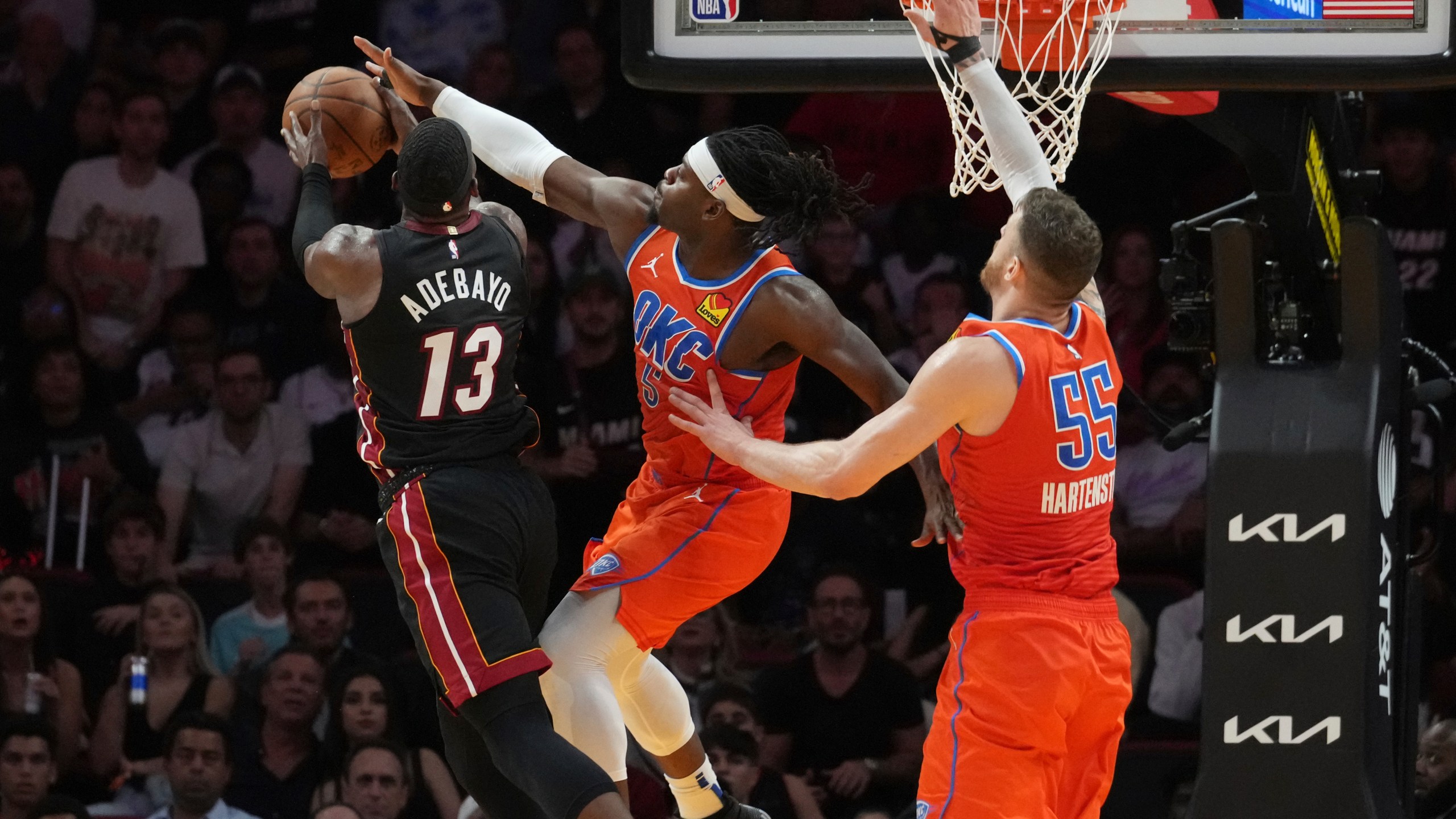 Oklahoma City Thunder guard Luguentz Dort (5) blocks a drive to the basket by Miami Heat center Bam Adebayo (13) during the first half of an NBA basketball game, Friday, Dec. 20, 2024, in Miami. (AP Photo/Marta Lavandier)