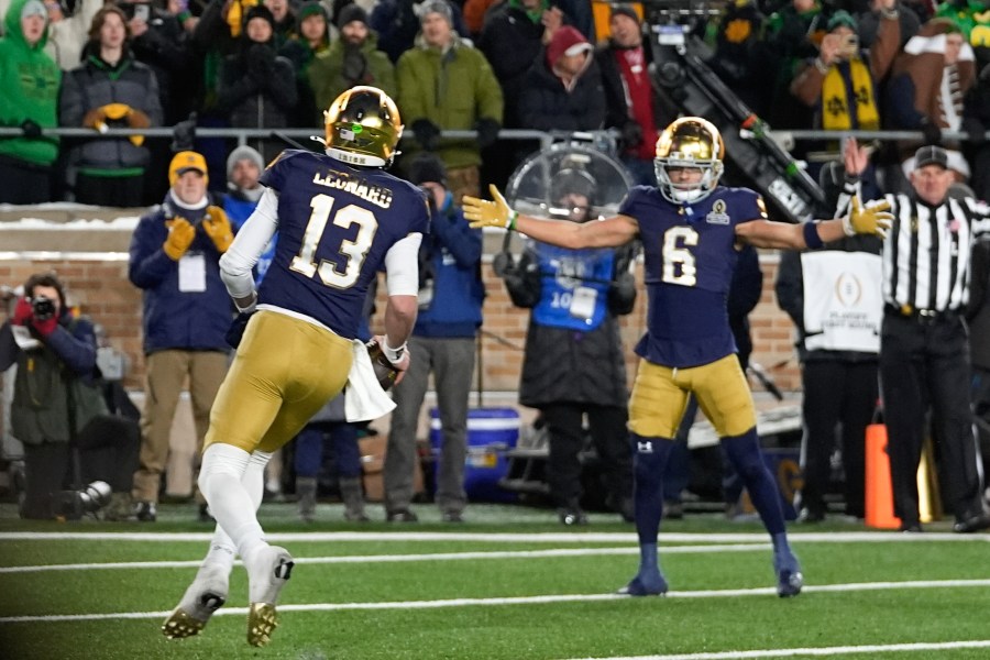 Notre Dame quarterback Riley Leonard (13) celebrates his one-yard touchdown run with Jordan Faison (6) against Indiana during the second half in the first round of the NCAA College Football Playoff, Friday, Dec. 20, 2024, in South Bend, Ind. (AP Photo/Darron Cummings)