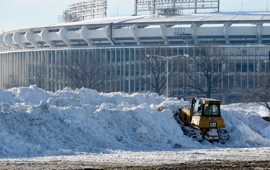 FILE - A vehicle pushes up pikes of snow after trucks dump their loads of snow in the parking lots of RFK Stadium in Washington, Monday, Jan. 25, 2016. (AP Photo/Susan Walsh, File)