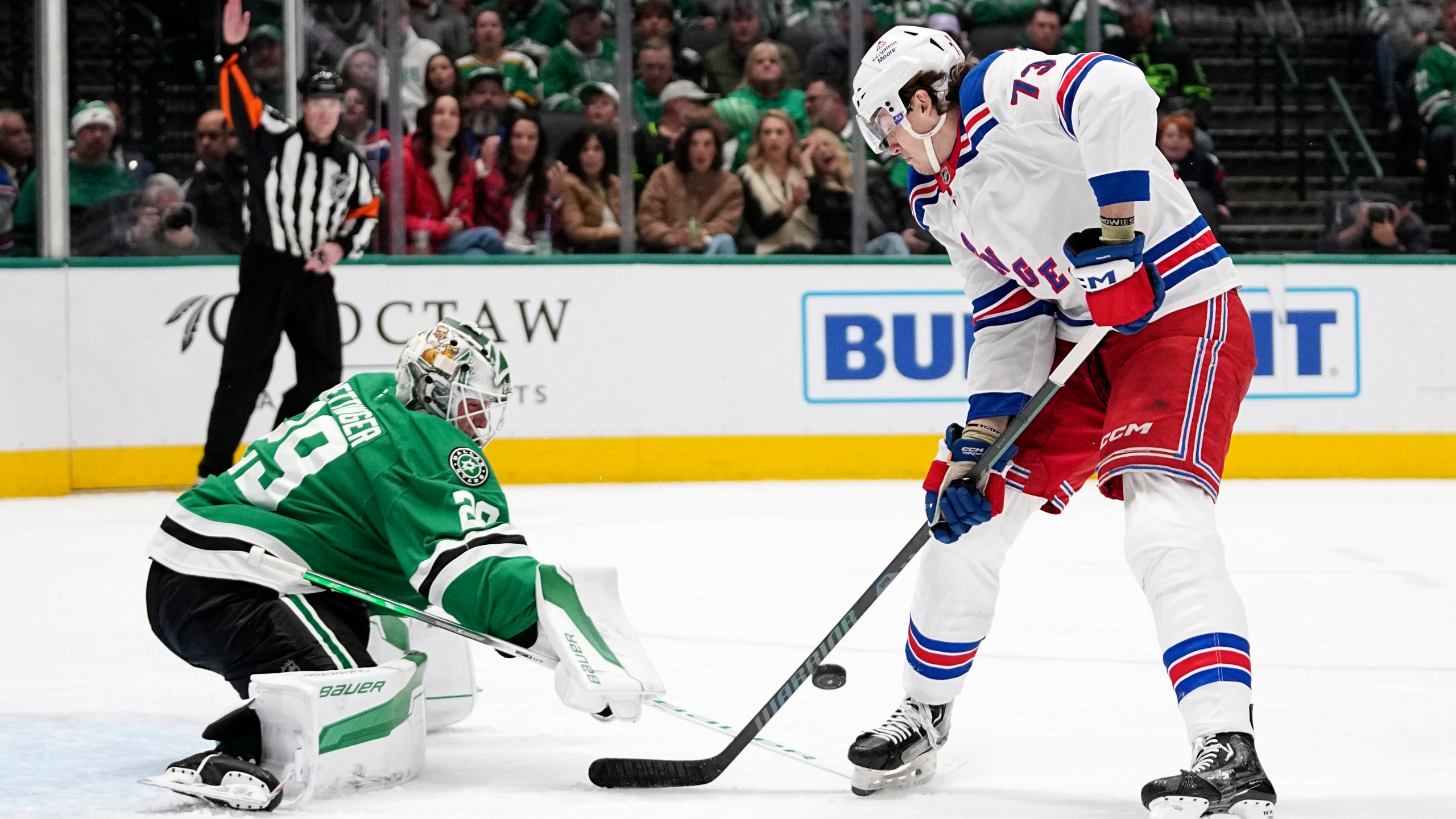 Dallas Stars goaltender Jake Oettinger (29) slaps the puck away on an attack by New York Rangers' Matt Rempe (73) in the second period of an NHL hockey game in Dallas, Friday, Dec. 20, 2024. (AP Photo/Tony Gutierrez)