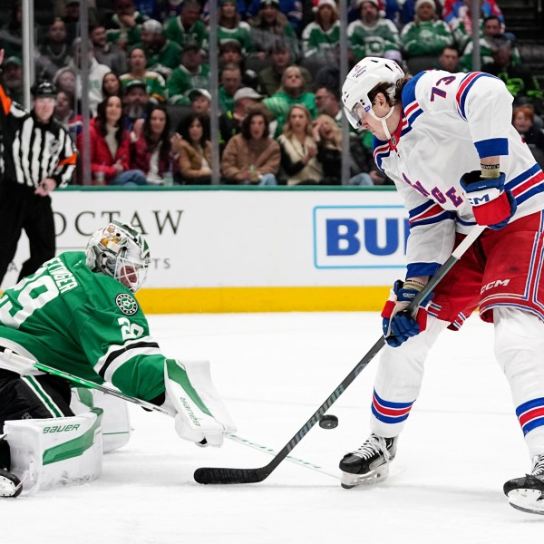 Dallas Stars goaltender Jake Oettinger (29) slaps the puck away on an attack by New York Rangers' Matt Rempe (73) in the second period of an NHL hockey game in Dallas, Friday, Dec. 20, 2024. (AP Photo/Tony Gutierrez)