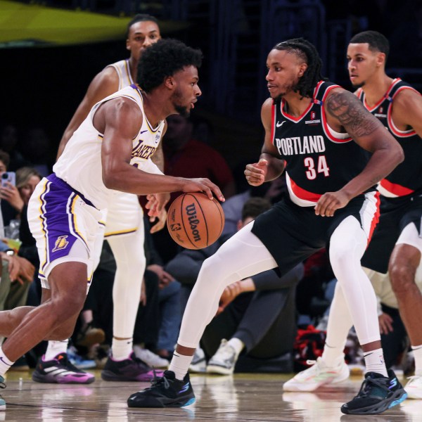 Los Angeles Lakers guard Bronny James, left, dribbles past Portland Trail Blazers' forward Jabari Walker during the second half of an NBA basketball game, Sunday, Dec. 8, 2024, in Los Angeles. (AP Photo/Etienne Laurent)