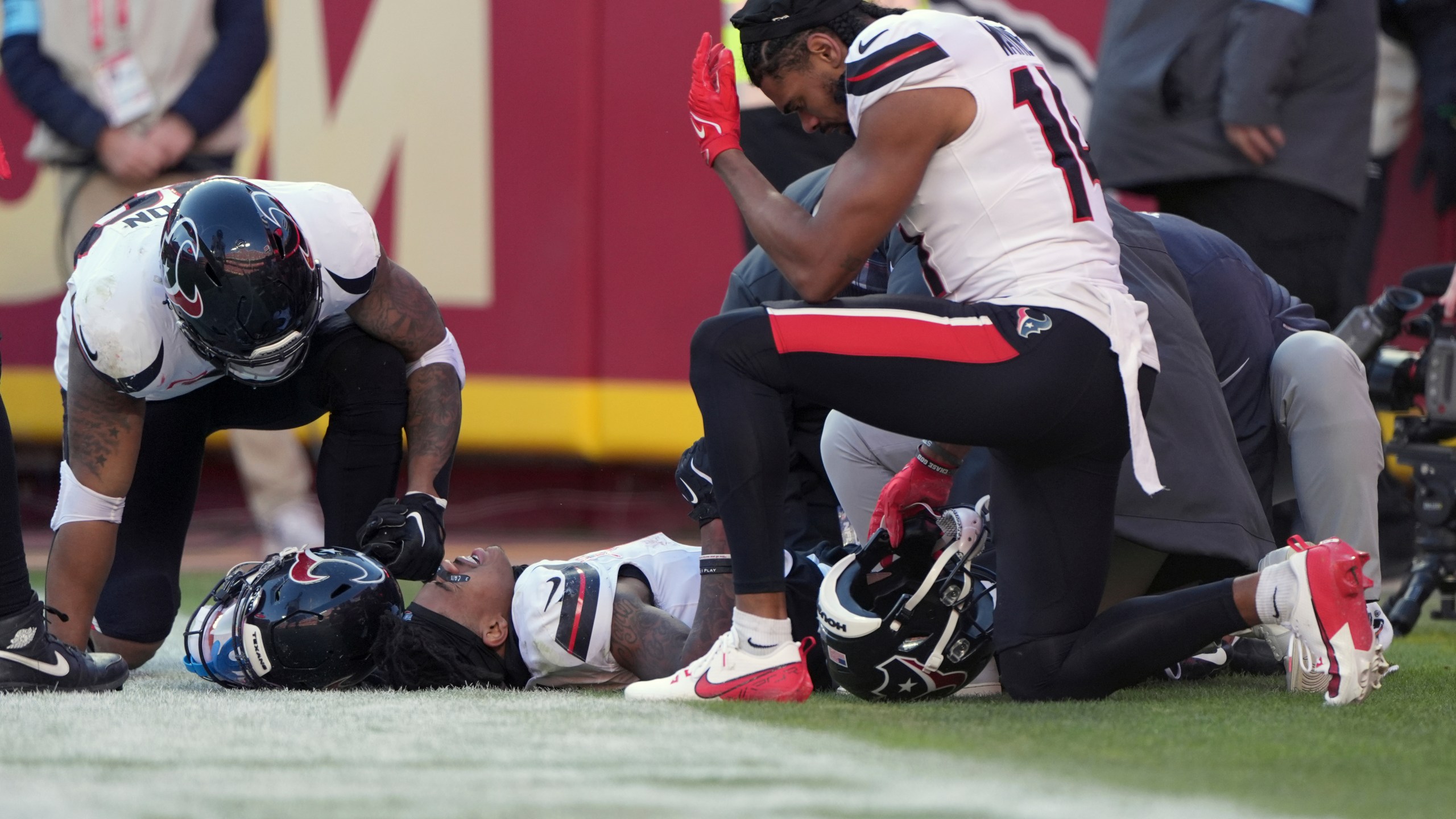 Houston Texans wide receiver Tank Dell is checked on by teammate Jared Wayne, right, after catching a touchdown pass and being injured during the second half of an NFL football game against the Kansas City Chiefs Saturday, Dec. 21, 2024, in Kansas City, Mo. (AP Photo/Charlie Riedel)