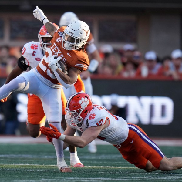 Texas running back Jaydon Blue (23) tries to break a tackle by Clemson linebacker Wade Woodaz (17) during the first half in the first round of the College Football Playoff, Saturday, Dec. 21, 2024, in Austin, Texas. (AP Photo/Eric Gay)