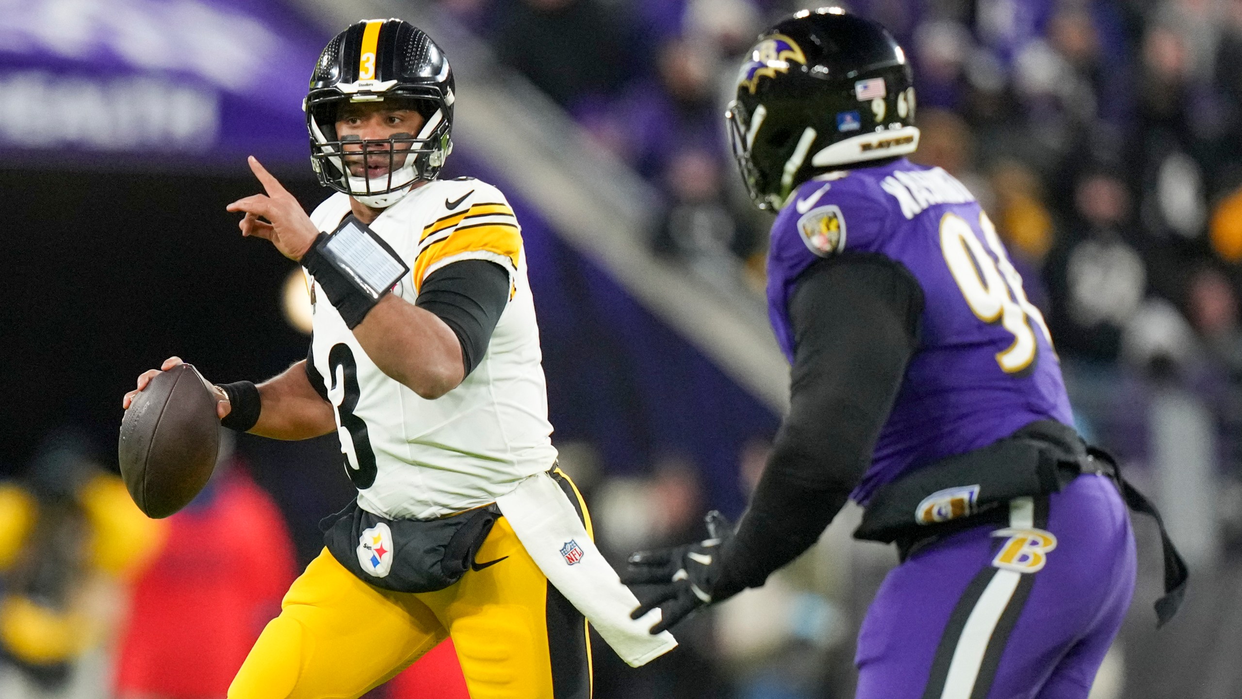 Pittsburgh Steelers quarterback Russell Wilson, left, gestures while scrambling against Baltimore Ravens defensive tackle Broderick Washington during the first half of an NFL football game, Saturday, Dec. 21, 2024, in Baltimore. (AP Photo/Stephanie Scarbrough)