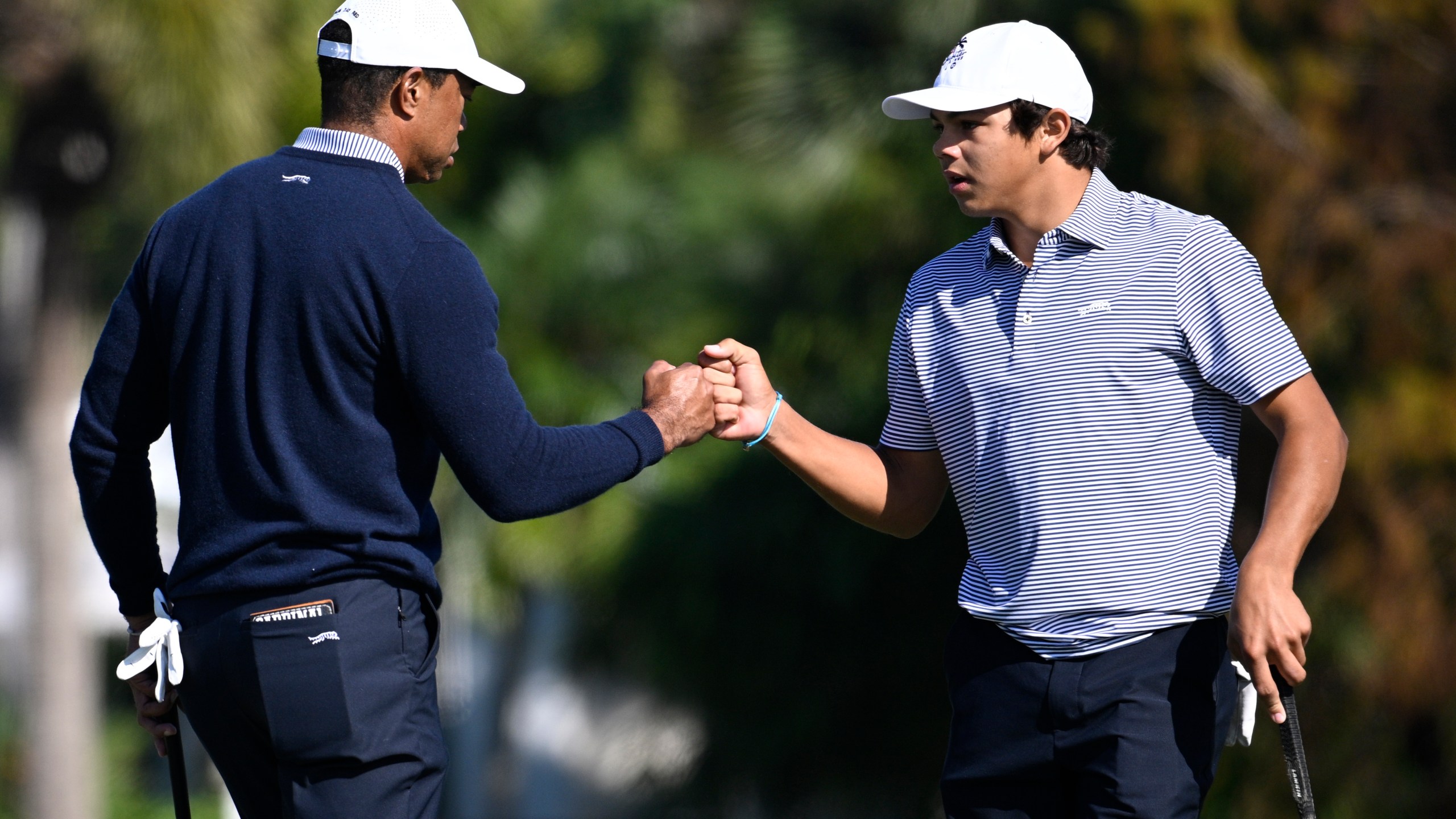 Charlie Woods, right, gets a fist bump from his father, Tiger Woods after making their putt on the fourth green during the first round of the PNC Championship golf tournament, Saturday, Dec. 21, 2024 in Orlando. (AP Photo/Phelan M. Ebenhack)