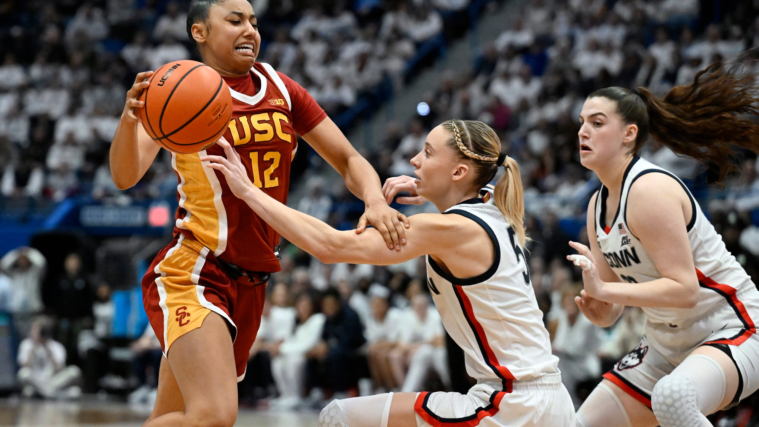 Southern California guard JuJu Watkins, left, drives to the basket as UConn guards Paige Bueckers, center, and Morgan Cheli, right, defend in the second half of an NCAA college basketball game, Saturday, Dec. 21, 2024, in Hartford, Conn. (AP Photo/Jessica Hill)