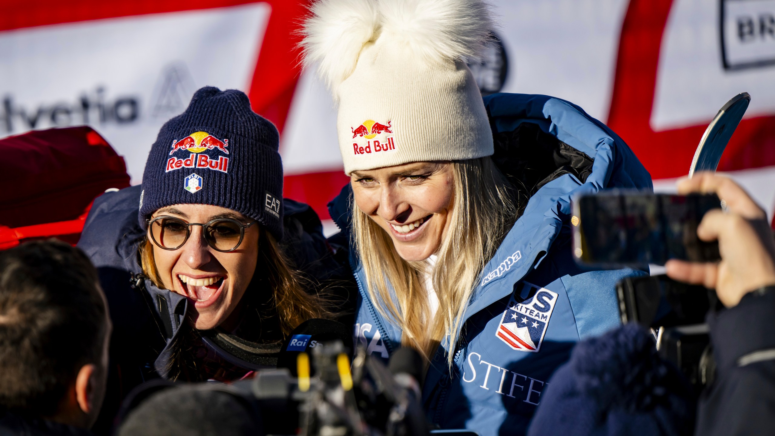 Sofia Goggia of Italy, left, and Lindsey Vonn of United States of America, talk with journalists after completing an alpine ski, women's World Cup super G, in St. Moritz, Switzerland, Saturday, Dec. 21, 2024. (Jean-Christophe Bott/Keystone via AP)