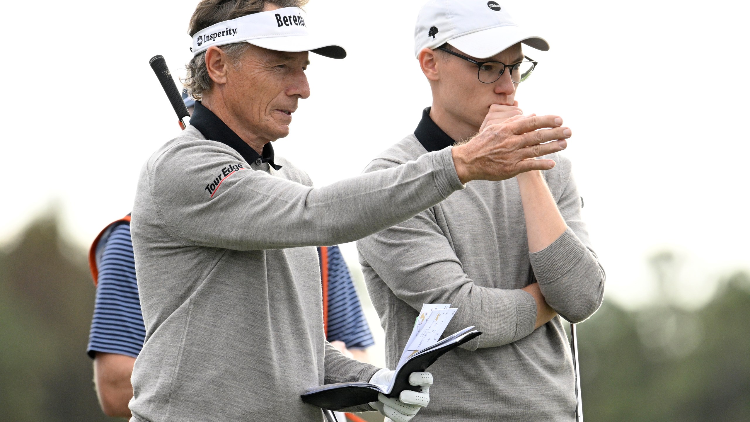 Bernhard Langer, left, and his son Jason Langer, right, discuss their shots before putting on the 14th green during the final round of the PNC Championship golf tournament, Sunday, Dec. 22, 2024, in Orlando, Fla. (AP Photo/Phelan M. Ebenhack)