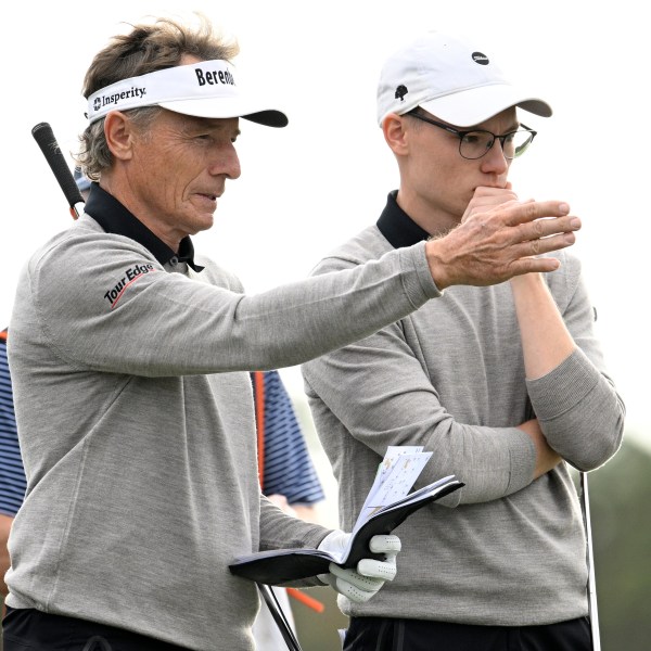 Bernhard Langer, left, and his son Jason Langer, right, discuss their shots before putting on the 14th green during the final round of the PNC Championship golf tournament, Sunday, Dec. 22, 2024, in Orlando, Fla. (AP Photo/Phelan M. Ebenhack)