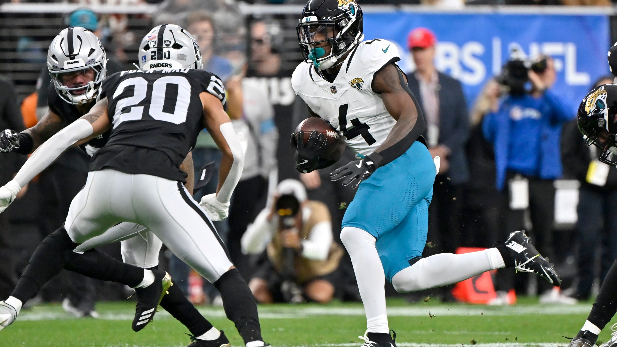 Jacksonville Jaguars running back Tank Bigsby (4) runs for a first down against the Las Vegas Raiders defense, including Raiders safety Isaiah Pola-Mao (20), during the first half of an NFL football game Sunday, Dec. 22, 2024, in Las Vegas. (AP Photo/David Becker)