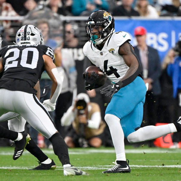 Jacksonville Jaguars running back Tank Bigsby (4) runs for a first down against the Las Vegas Raiders defense, including Raiders safety Isaiah Pola-Mao (20), during the first half of an NFL football game Sunday, Dec. 22, 2024, in Las Vegas. (AP Photo/David Becker)