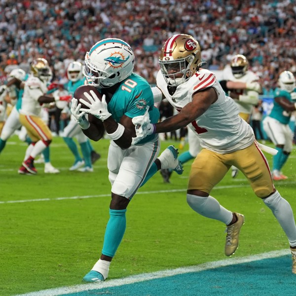 Miami Dolphins wide receiver Tyreek Hill (10) catches a pass for a touchdown as San Francisco 49ers cornerback Charvarius Ward (7) gives him a push during the first half of an NFL football game, Sunday, Dec. 22, 2024, in Miami Gardens, Fla. (AP Photo/Rebecca Blackwell)