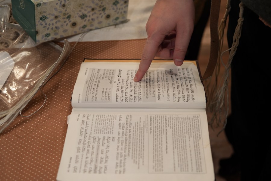 Dov Marcus points to prayers as he reads from the Jewish prayer book in Teaneck, N.J., on Friday, Dec. 20, 2024. (AP Photo/Luis Andres Henao)