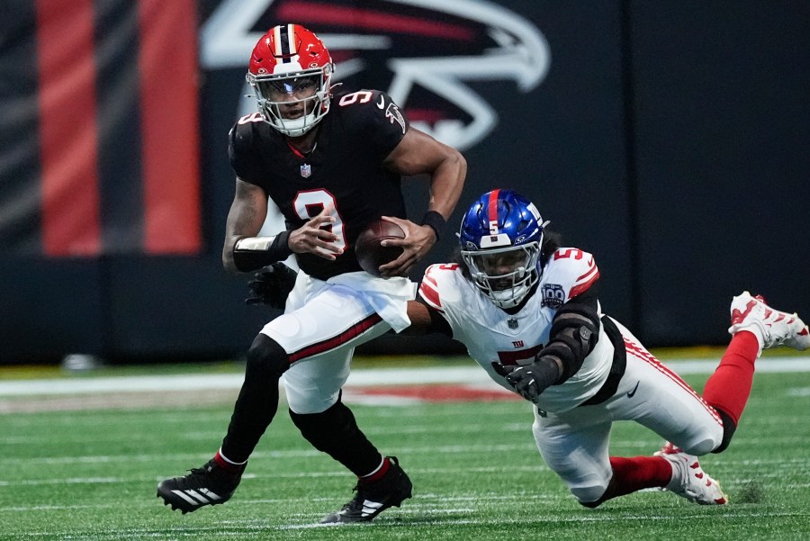 Atlanta Falcons quarterback Michael Penix Jr. (9) tackled by New York Giants linebacker Kayvon Thibodeaux (5) short of the first down in the first half of an NFL football game in Atlanta, Sunday, Dec. 22, 2024. (AP Photo/John Bazemore)