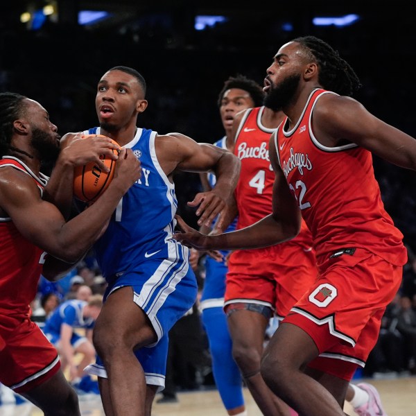 Ohio State's Bruce Thornton, left, fights for control of the ball with Kentucky's Lamont Butler as Evan Mahaffey, right, watches during the first half of an NCAA college basketball game in the CBS Sports Classic, Saturday, Dec. 21, 2024, in New York. (AP Photo/Frank Franklin II)