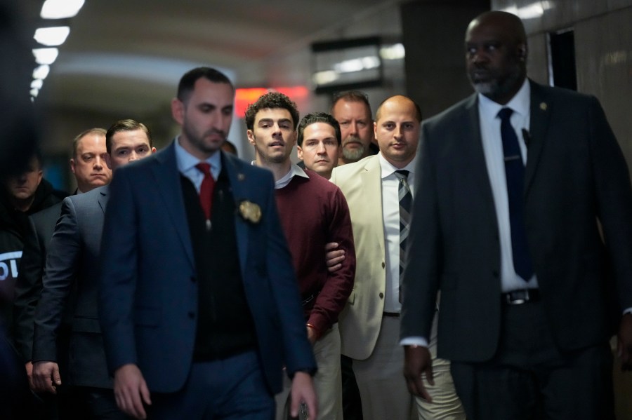 Luigi Mangione, center, is escorted into Manhattan Criminal court for his arraignment on state murder and terror charges in the killing of UnitedHealthcare CEO Brian Thompson, Monday, Dec. 23, 2024, in New York. (AP Photo/Seth Wenig)