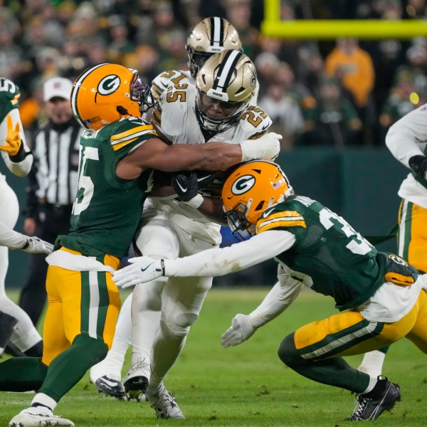 New Orleans Saints running back Kendre Miller (25) is stopped by Green Bay Packers linebacker Eric Wilson and safety Zayne Anderson, right, during the first half of an NFL football game, Monday, Dec. 23, 2024, in Green Bay, Wis. (AP Photo/Morry Gash)