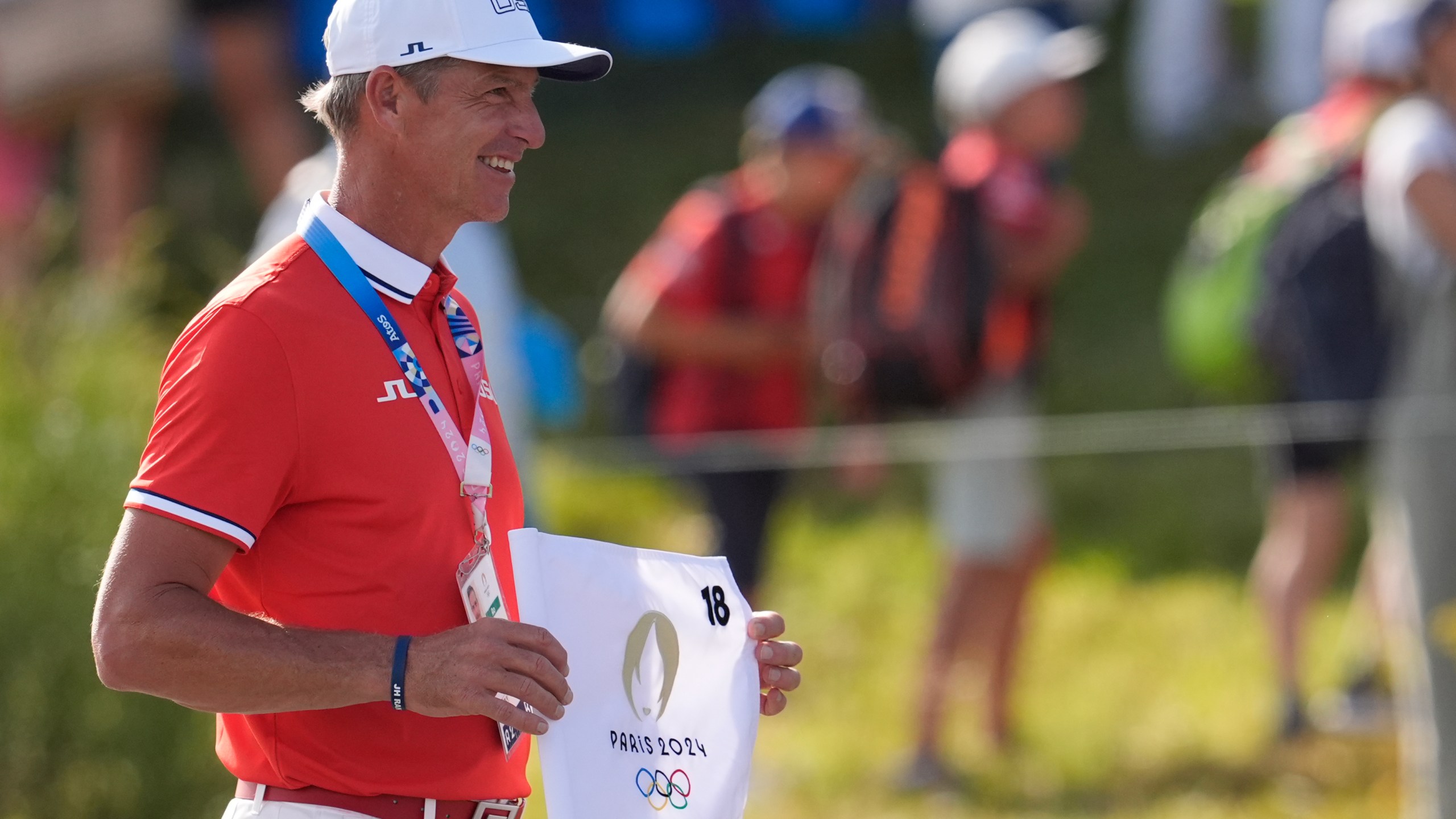 FILE - Ted Scott caddie for gold medalist Scottie Scheffler, of the United States, poses with the 18th hole flag after the end of the men's golf at the 2024 Summer Olympics, Sunday, Aug. 4, 2024, at Le Golf National in Saint-Quentin-en-Yvelines, France. (AP Photo/George Walker IV, File)