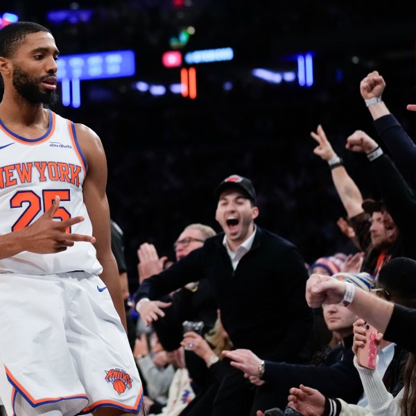 New York Knicks' Mikal Bridges, left, and fans react after Bridges hit a three point basket during the second half of an NBA basketball game, Wednesday, Dec. 25, 2024, in New York. The Knicks defeated the Spurs 117-114. (AP Photo/Seth Wenig)