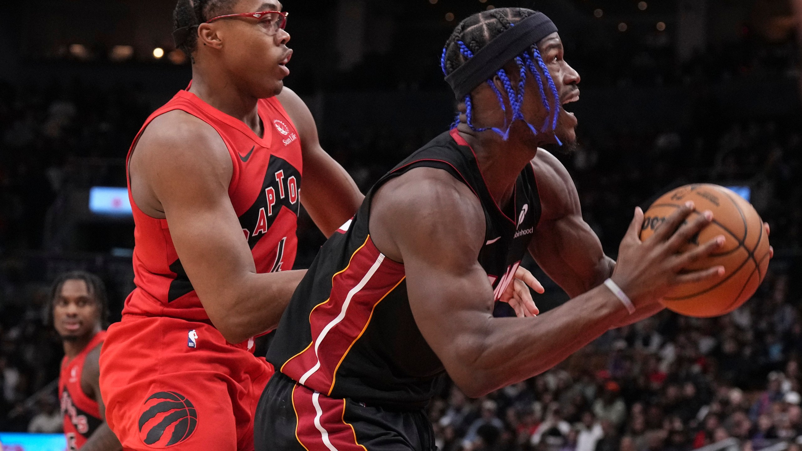 Miami Heat's Jimmy Butler, right, drives to the net against Toronto Raptors' Scottie Barnes, front left, during second-half NBA basketball game action in Toronto, Sunday, Dec. 1, 2024. (Chris Young/The Canadian Press via AP)