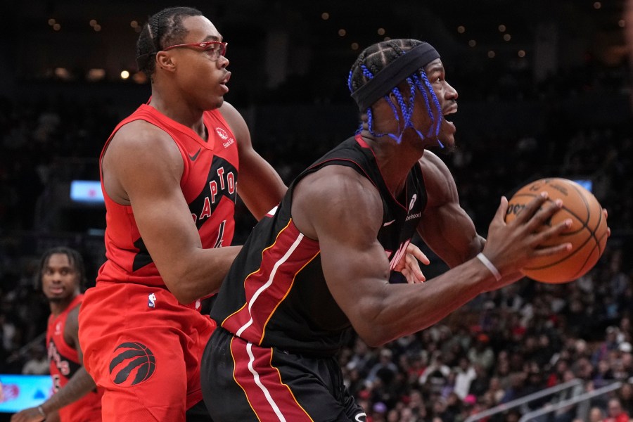 Miami Heat's Jimmy Butler, right, drives to the net against Toronto Raptors' Scottie Barnes, front left, during second-half NBA basketball game action in Toronto, Sunday, Dec. 1, 2024. (Chris Young/The Canadian Press via AP)