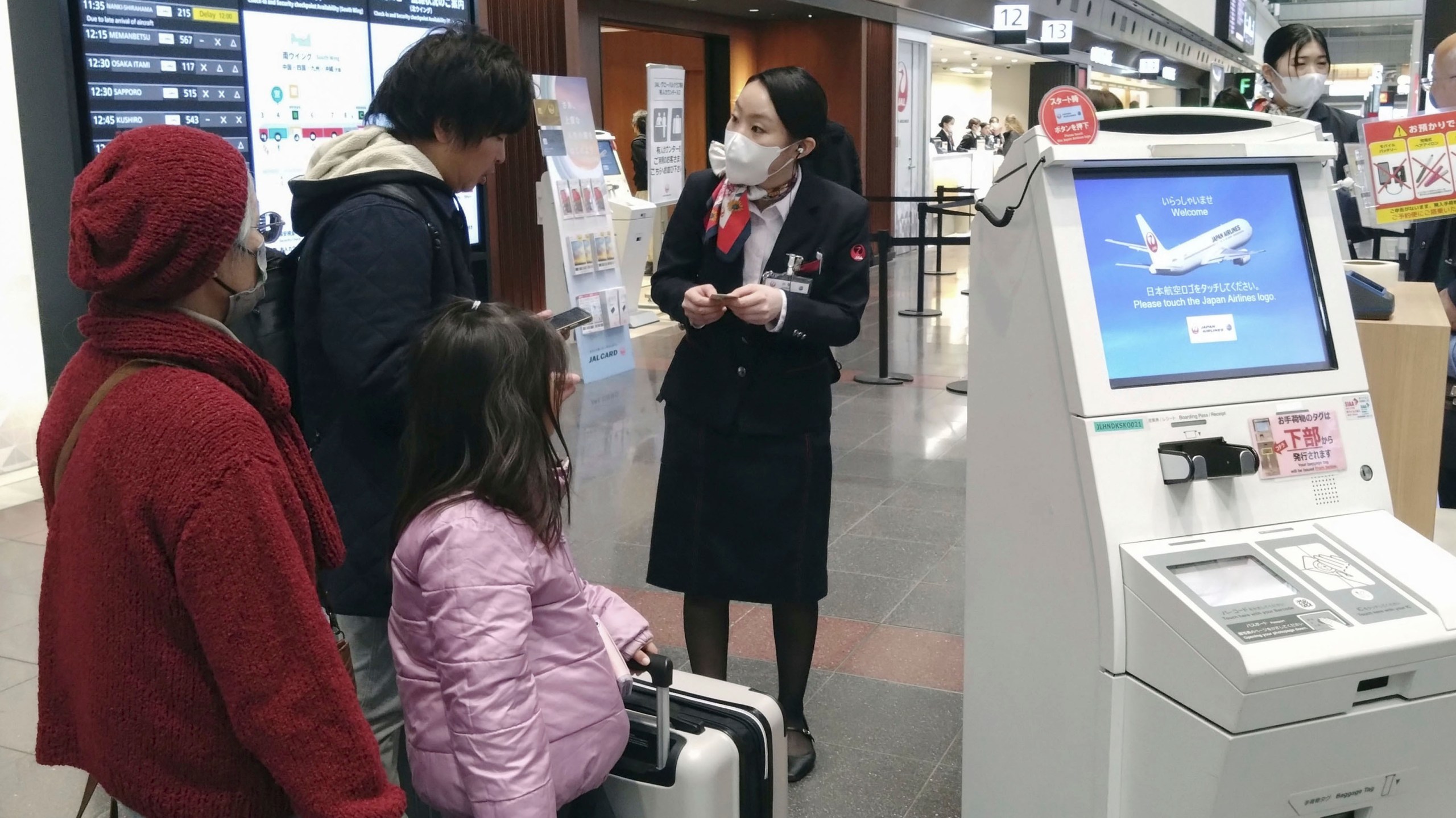 A staff member of Japan Airlines helps customers at the Haneda airport in Tokyo, Thursday, Dec. 26, 2024, after the airlines said it was hit by a cyberattack. (Shingo Fukuma/Kyodo News via AP)