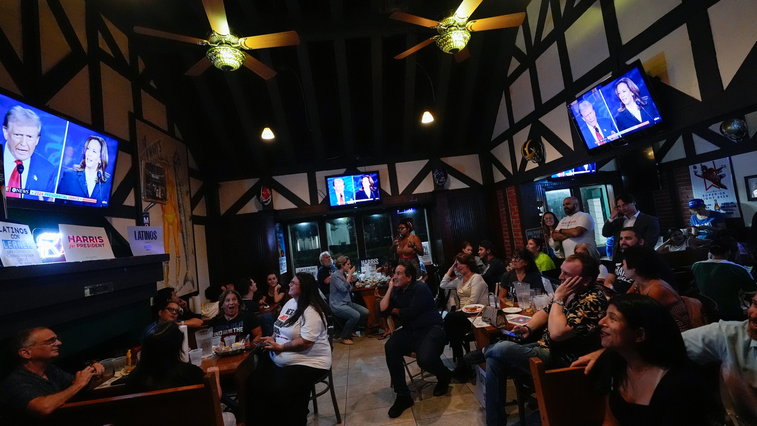 FILE - People watch TV screens showing a debate between Democratic presidential nominee Vice President Kamala Harris, right on screen, and Republican presidential nominee former President Donald Trump, at Sports Grill Kendall, where the Miami-Dade Democratic Hispanic Caucus had organized a watch party, Tuesday, Sept. 10, 2024, in Miami. (AP Photo/Rebecca Blackwell, File)