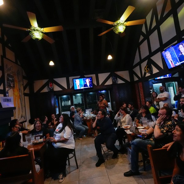 FILE - People watch TV screens showing a debate between Democratic presidential nominee Vice President Kamala Harris, right on screen, and Republican presidential nominee former President Donald Trump, at Sports Grill Kendall, where the Miami-Dade Democratic Hispanic Caucus had organized a watch party, Tuesday, Sept. 10, 2024, in Miami. (AP Photo/Rebecca Blackwell, File)