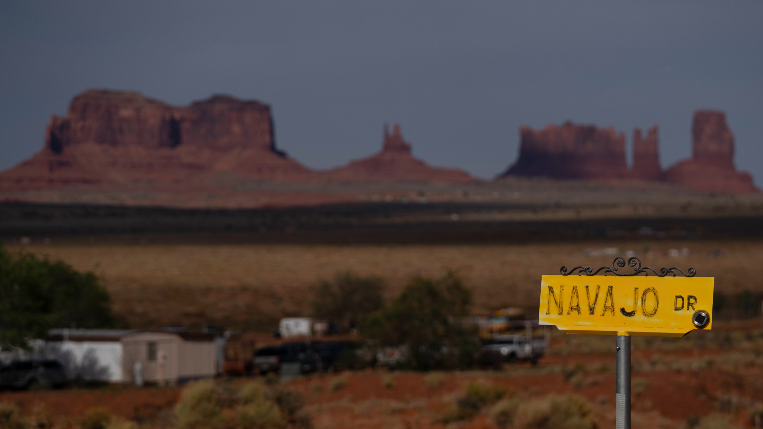 FILE - A sign marks Navajo Drive, as Sentinel Mesa stands in the distance in Oljato-Monument Valley, Utah on the Navajo Reservation, April 30, 2020. (AP Photo/Carolyn Kaster, File)