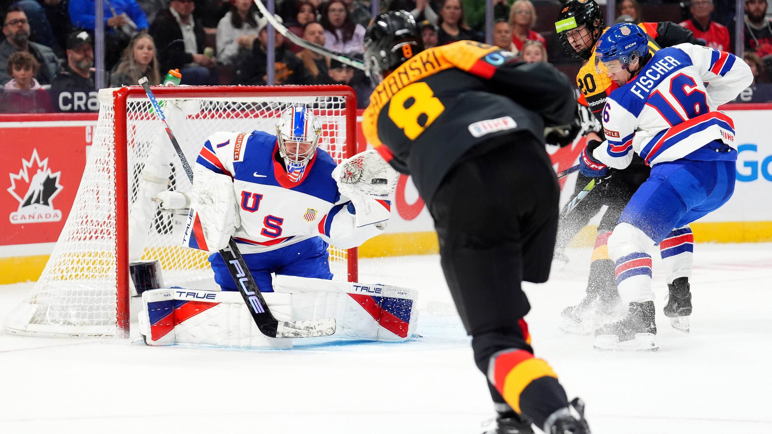 United Sttaes goaltender Trey Augustine (1) makes a glove-save against Germany forward Noah Samanski (8) during second-period IIHF World Junior Hockey Championship preliminary round game action in Ottawa, Ontario, Thursday, Dec. 26, 2024. (Sean Kilpatrick/The Canadian Press via AP)