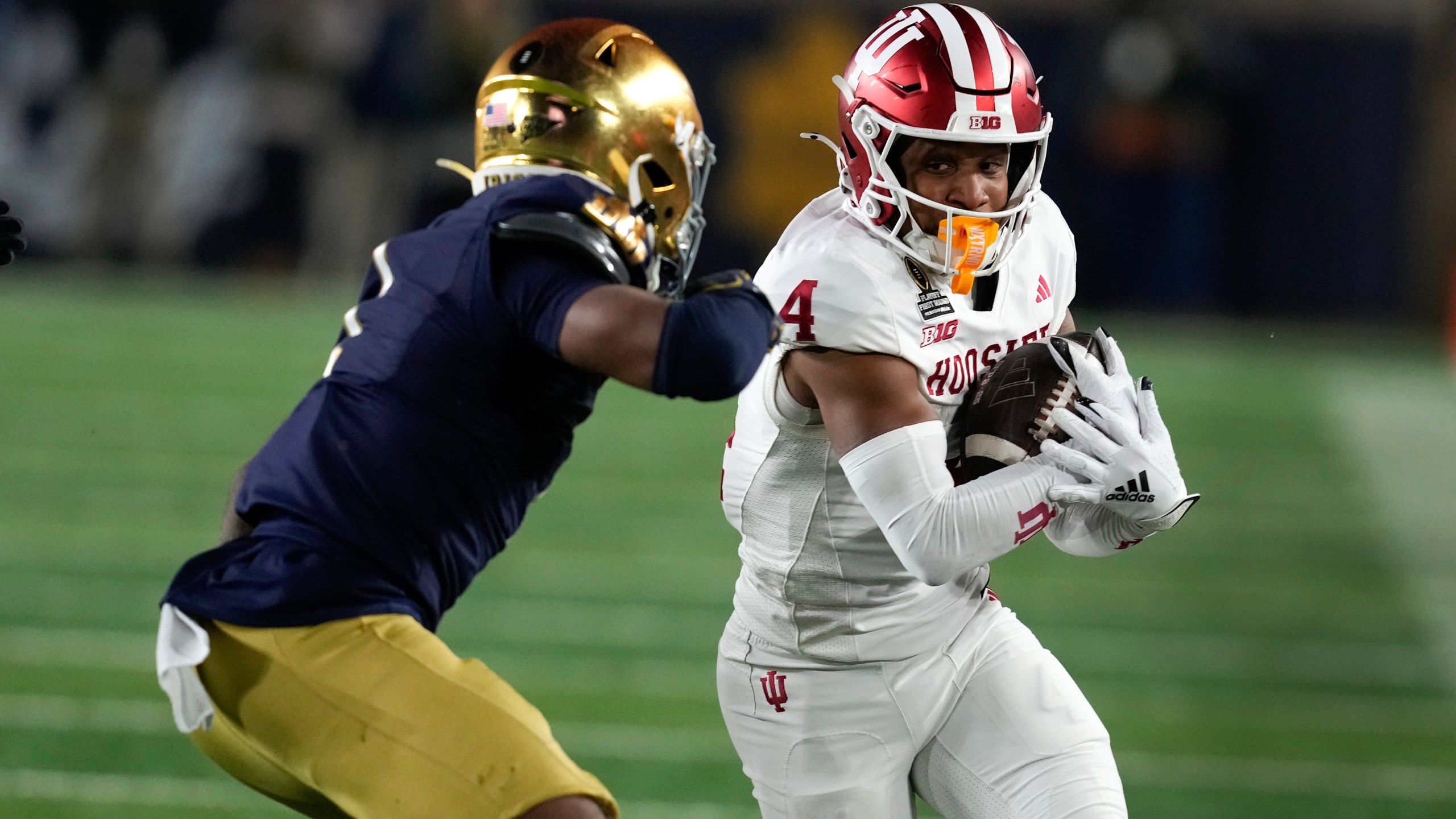 Indiana wide receiver Myles Price (4) protects the ball from Notre Dame safety Jordan Clark (1) during the first half in the first round of the College Football Playoff, Friday, Dec. 20, 2024, in South Bend, Ind. (AP Photo/Darron Cummings)