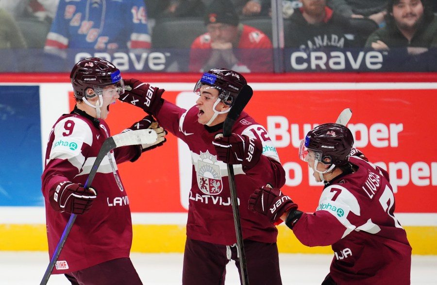 Latvia's Eriks Mateiko, left, celebrates his game-winning shootout goal against Canada with Toms Mots (12) and Davids Livsics (7) in a IIHF World Junior Hockey Championship preliminary round game in Ottawa, Ontario on Friday, Dec. 27, 2024. (Sean Kilpatrick/The Canadian Press via AP)