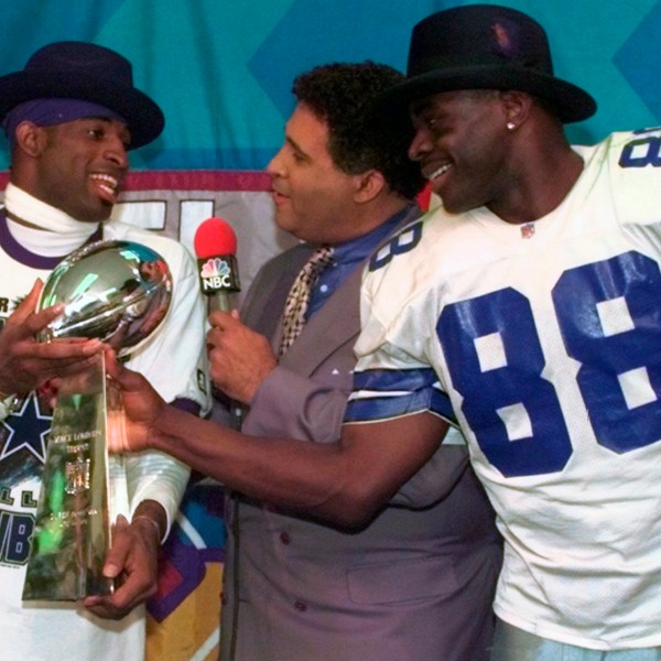 FILE - Dallas Cowboys cornerback Deion Sanders, left, and running back Michael Irvin (88) share the Vince Lombardi trophy as NBC commentator Greg Gumbel interviews the two after Super Bowl XXX in Tempe, Ariz., Sunday, Jan. 28, 1996. (AP Photo/Ron Heflin, File)