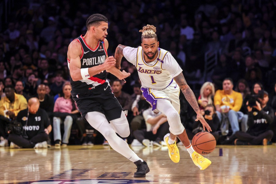 Los Angeles Lakers guard D'Angelo Russell, right, dribbles past Portland Trail Blazers forward Toumani Camara, left, during the first half of an NBA basketball game, Sunday, Dec. 8, 2024, in Los Angeles. (AP Photo/Etienne Laurent)