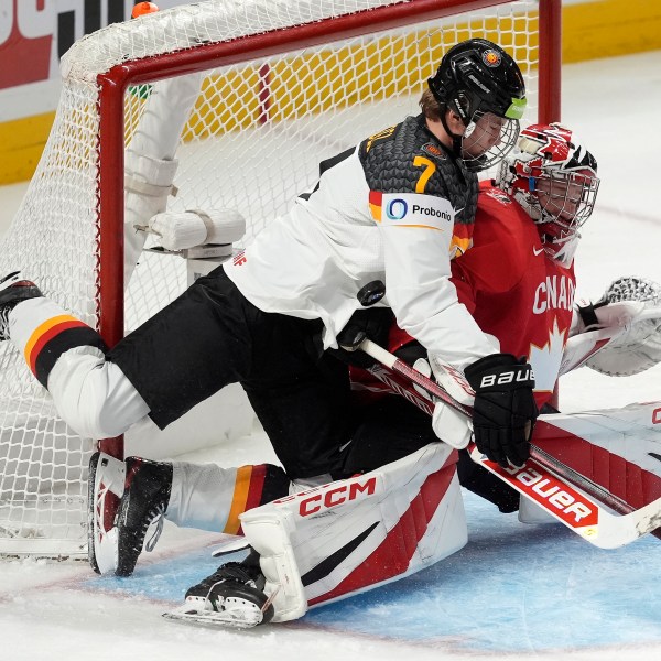 The puck hits Germany defenseman Carlos Handel (7) as he collides with Canada goaltender Carter George during first-period IIHF World Junior Hockey Championship tournament game action in Ottawa, Ontario, Sunday, Dec. 29, 2024. (Adrian Wyld/The Canadian Press via AP)