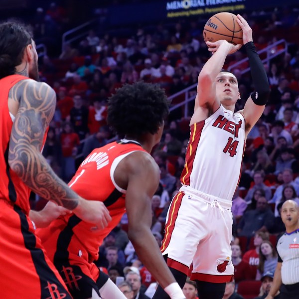 Miami Heat guard Tyler Herro (14) shoots a three-point shot as Houston Rockets center Steven Adams (12) and forward Amen Thompson, center, look on during the first half of an NBA basketball game Sunday, Dec. 29, 2024, in Houston. (AP Photo/Michael Wyke)