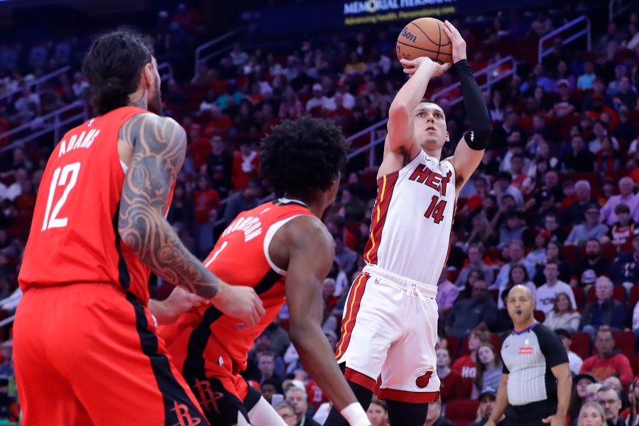 Miami Heat guard Tyler Herro (14) shoots a three-point shot as Houston Rockets center Steven Adams (12) and forward Amen Thompson, center, look on during the first half of an NBA basketball game Sunday, Dec. 29, 2024, in Houston. (AP Photo/Michael Wyke)