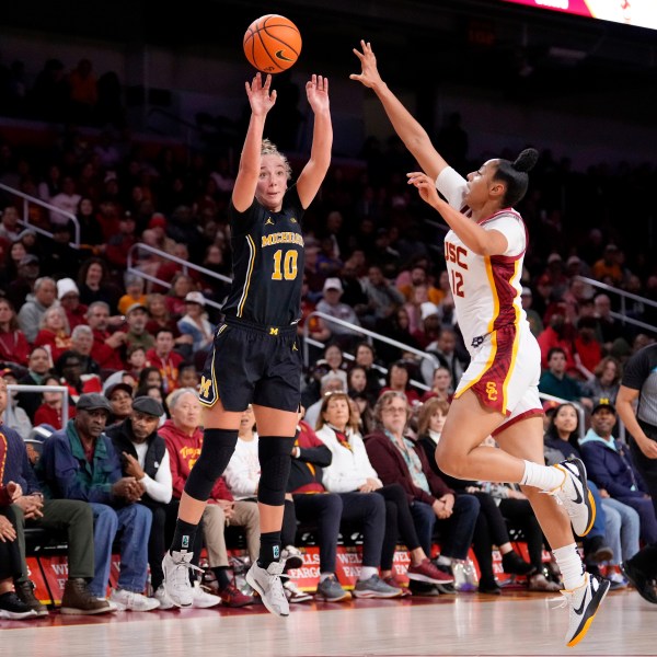 Michigan guard Jordan Hobbs, left, shoots as Southern California guard JuJu Watkins defends during the first half of an NCAA college basketball game, Sunday, Dec. 29, 2024, in Los Angeles. (AP Photo/Mark J. Terrill)