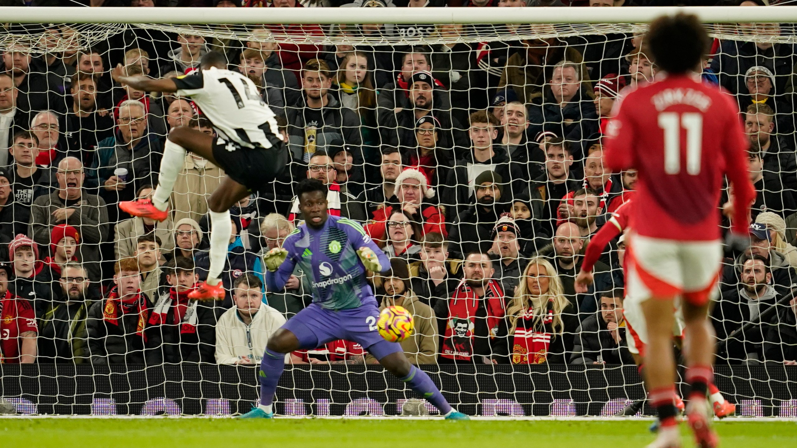 Newcastle's Alexander Isak, left, scores his side's opening goal during the English Premier League soccer match between Manchester United and Newcastle at the Old Trafford stadium in Manchester, England, Monday, Dec. 30, 2024. (AP Photo/Dave Thompson)